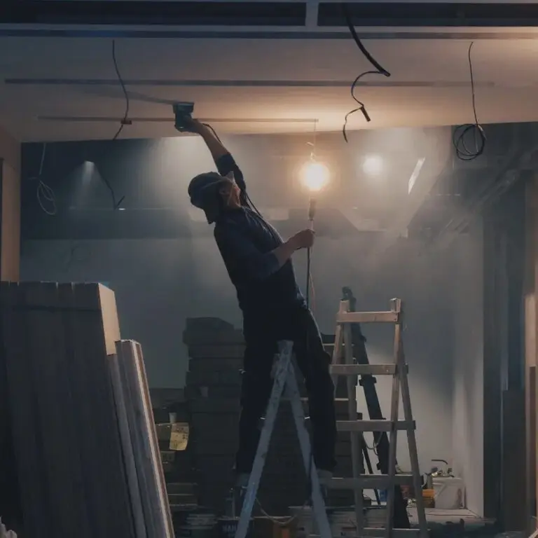 Man sanding drywall overhead